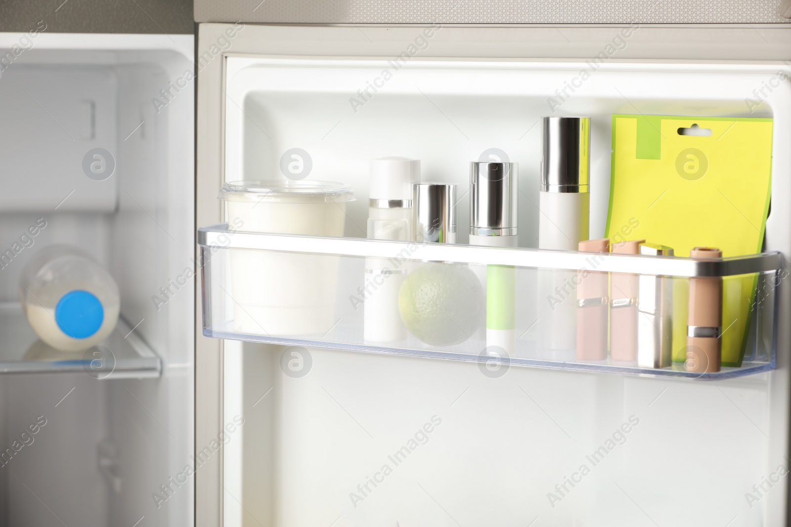 Photo of Different cosmetic products on shelf in refrigerator