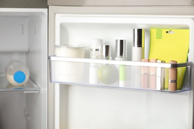 Photo of Different cosmetic products on shelf in refrigerator