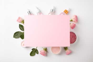 Composition with rose essential oil and blank card on white background, top view. Space for text