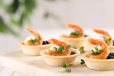 Delicious canapes with shrimps and black caviar on table, closeup