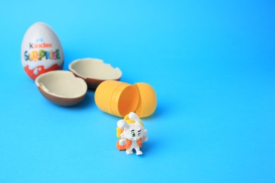 Photo of Slynchev Bryag, Bulgaria - May 25, 2023: Kinder Surprise Eggs, plastic capsule and toy bunny on light blue background, space for text