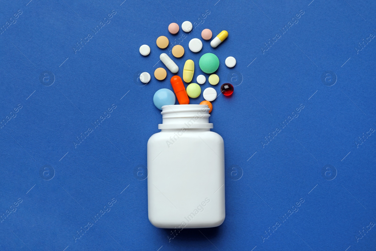 Photo of Bottle with different pills on color background, flat lay