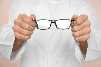 Male ophthalmologist with eyeglasses on light background, closeup