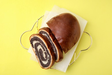 Photo of Slices of poppy seed roll on yellow background, top view. Tasty cake
