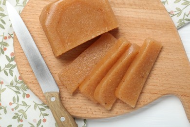 Photo of Tasty sweet quince paste and knife on white wooden table, top view