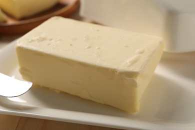 Photo of Block of tasty butter on plate, closeup