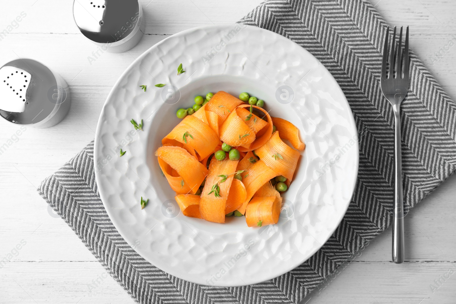 Photo of Tasty salad with fresh carrot in plate on table, top view