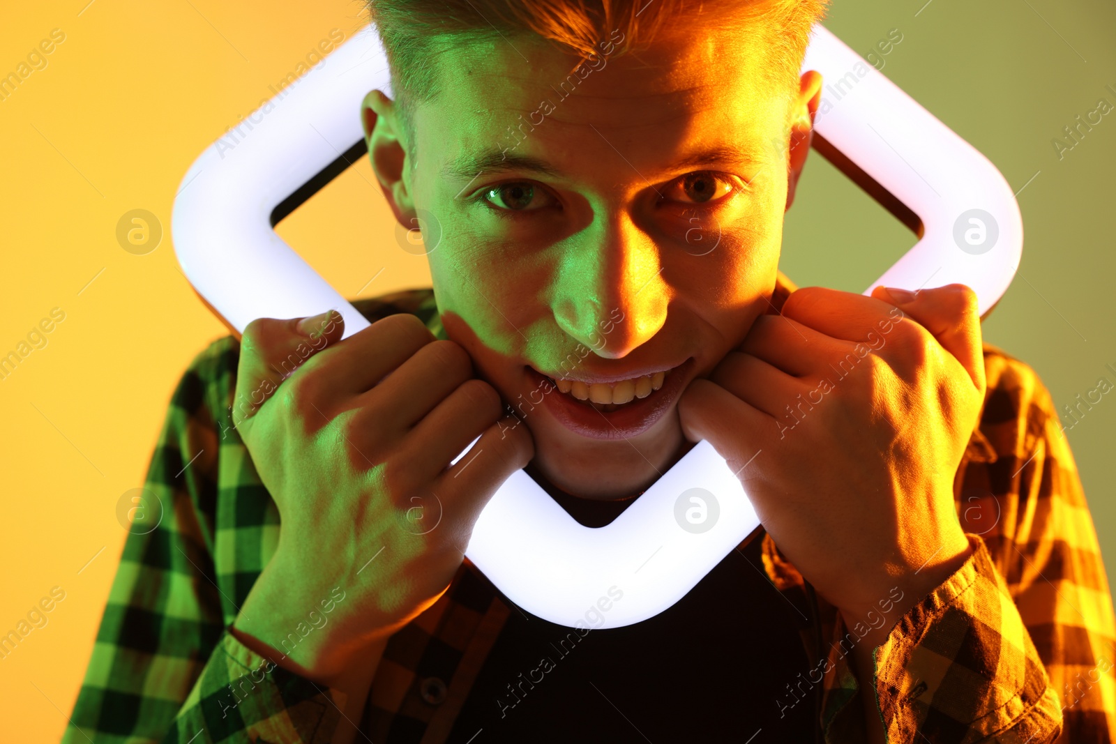 Photo of Young man with square lamp on color background in neon lights