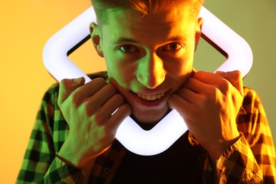 Photo of Young man with square lamp on color background in neon lights