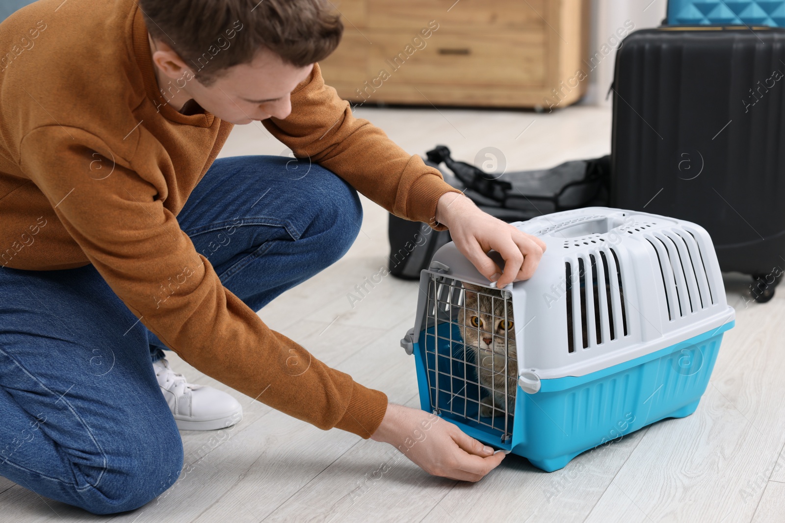 Photo of Travel with pet. Man closing carrier with cat at home