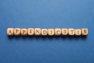 Photo of Word Appendicitis made of wooden cubes with letters on blue background, top view