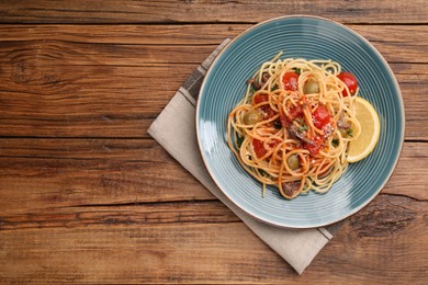 Delicious pasta with anchovies, tomatoes and parmesan cheese on wooden table, top view. Space for text