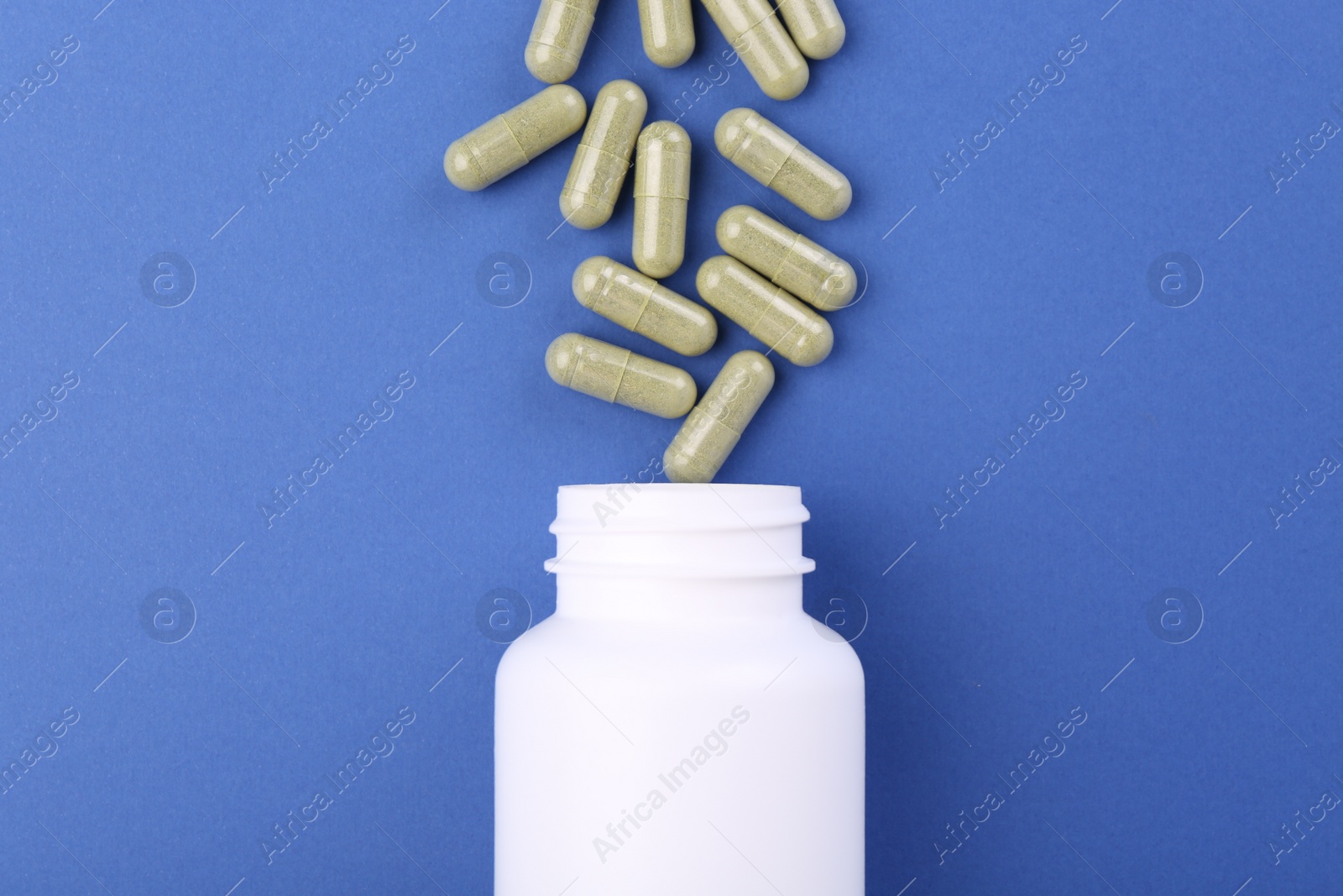 Photo of Bottle and vitamin capsules on blue background, top view