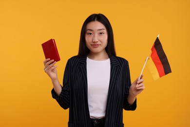 Immigration to Germany. Woman with passport and flag on orange background