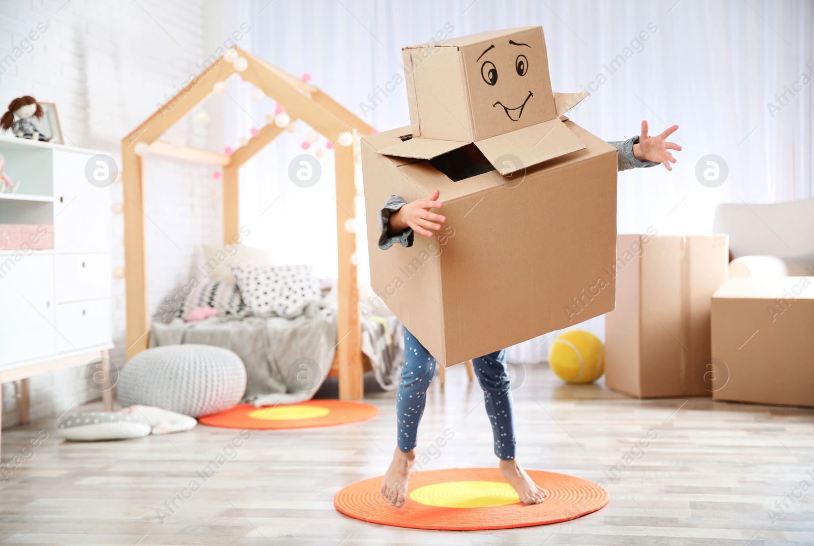 Photo of Cute little child wearing cardboard costume in bedroom