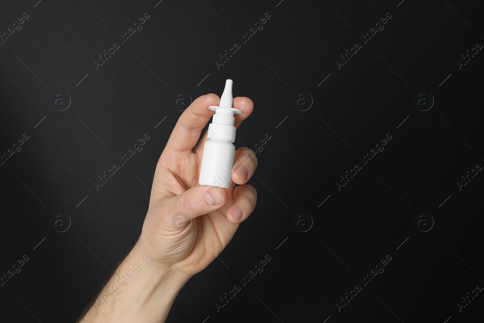 Photo of Man holding nasal spray on black background, closeup. Space for text