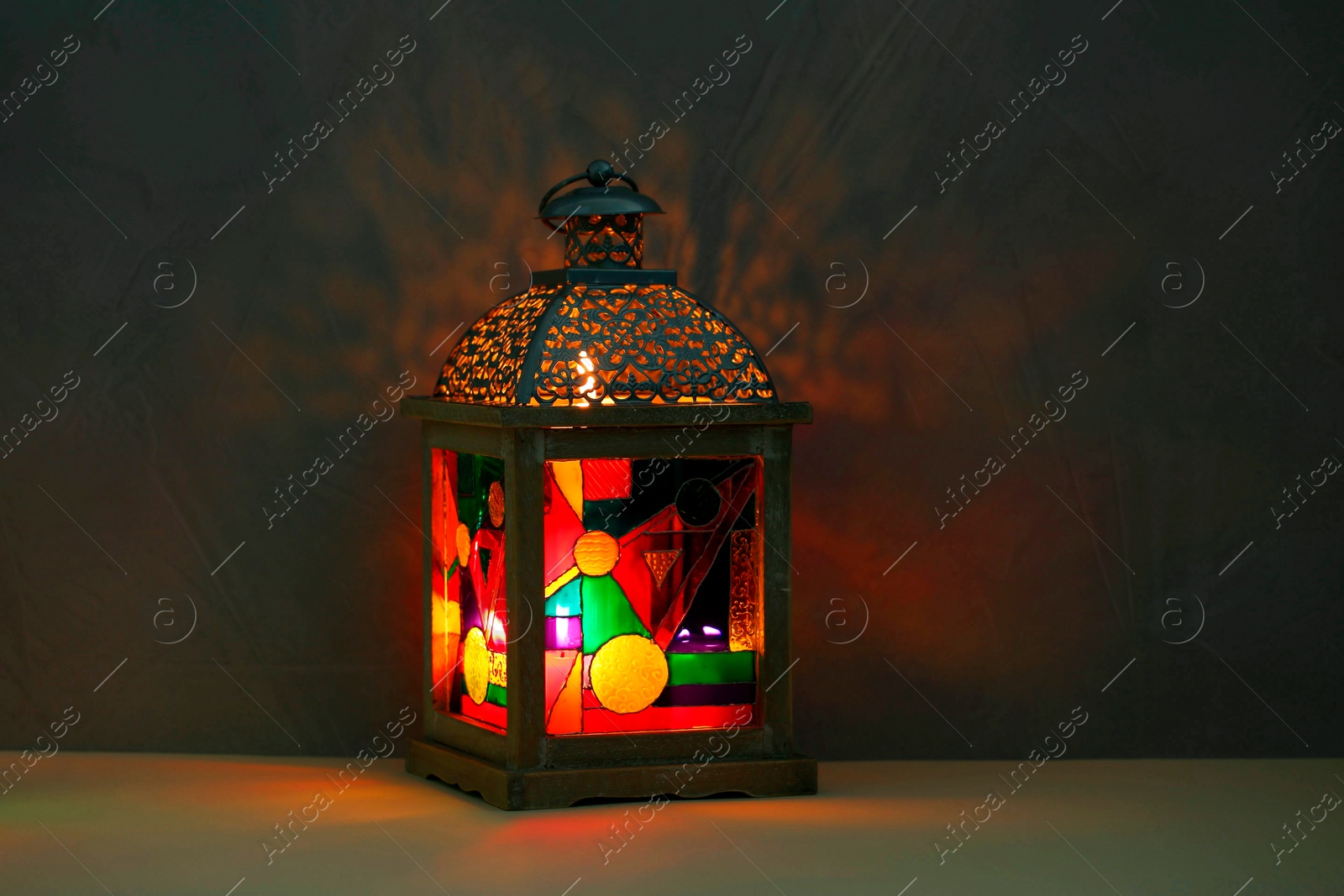 Photo of Decorative Arabic lantern on table against dark background. Space for text