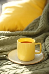 Cup of aromatic tea on green blanket, space for text