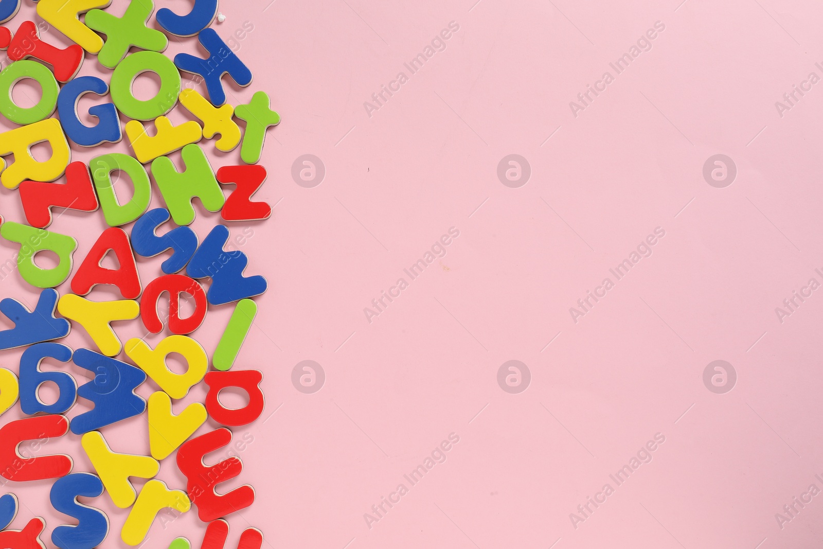Photo of Learning alphabet. Magnetic letters on pink background, flat lay. Space for text