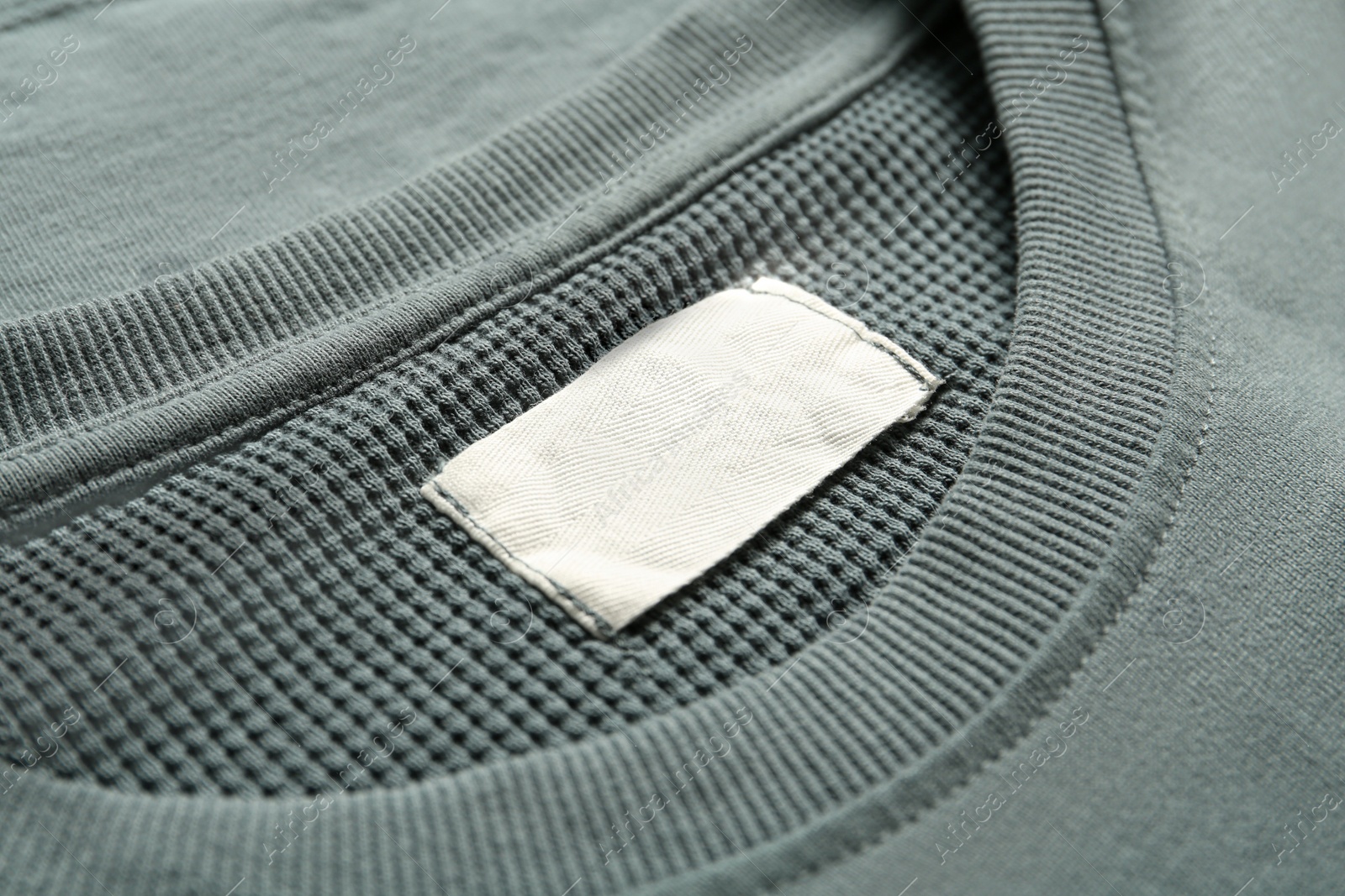 Photo of Blank clothing label on grey sweater, closeup