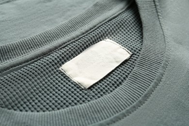 Blank clothing label on grey sweater, closeup