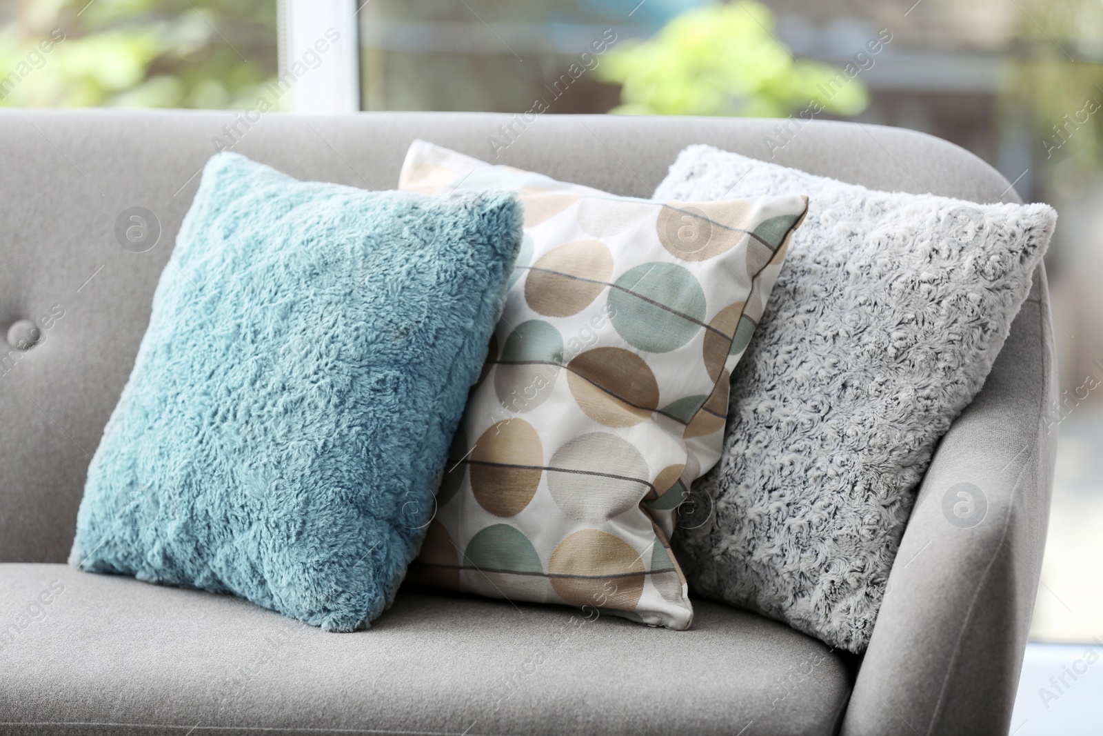 Photo of Different soft pillows on sofa in room. Interior element