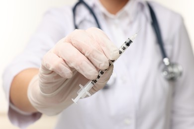 Doctor holding medical syringe on white background, closeup