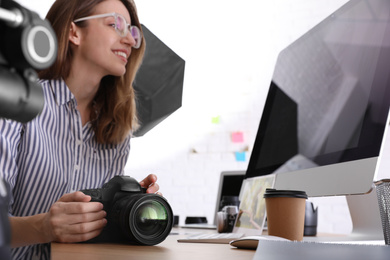 Photo of Professional photographer working at table in office, focus on camera