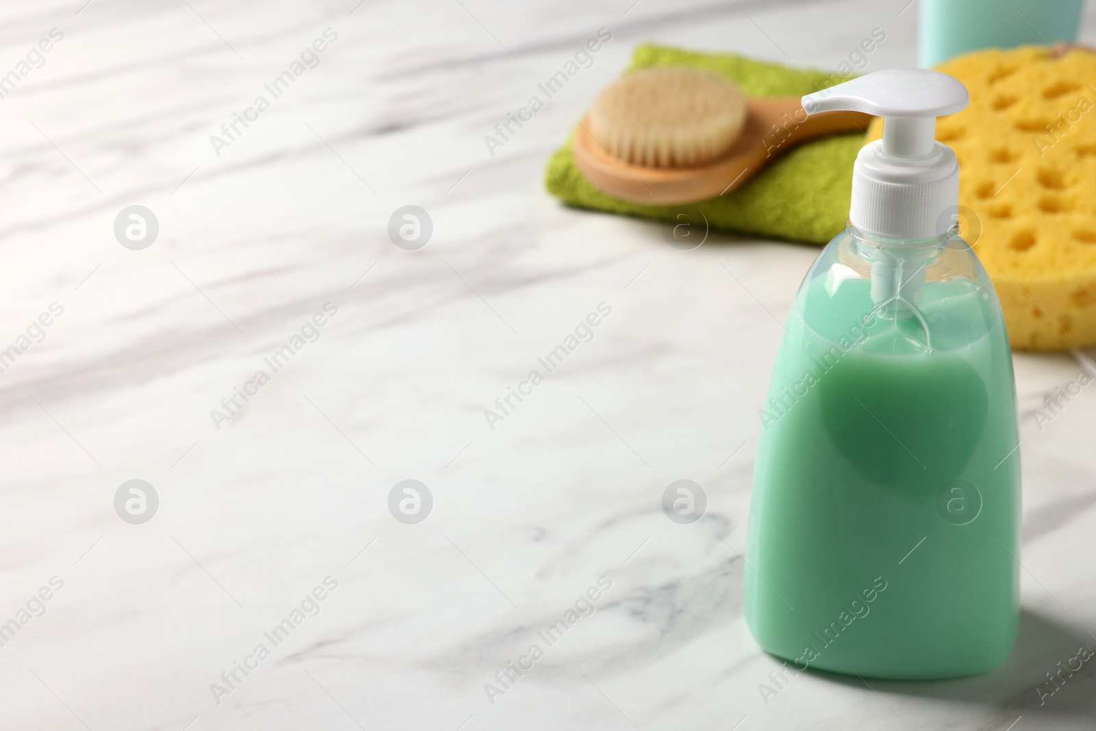 Photo of Dispenser of liquid soap on white marble table, space for text