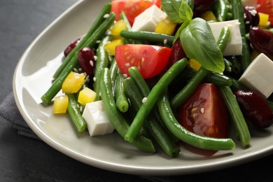 Photo of Plate of tasty salad with green beans on black table, closeup