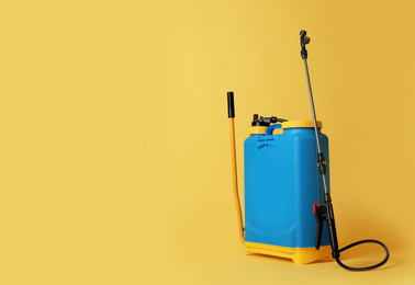 Photo of Manual insecticide sprayer on yellow background, space for text. Pest control