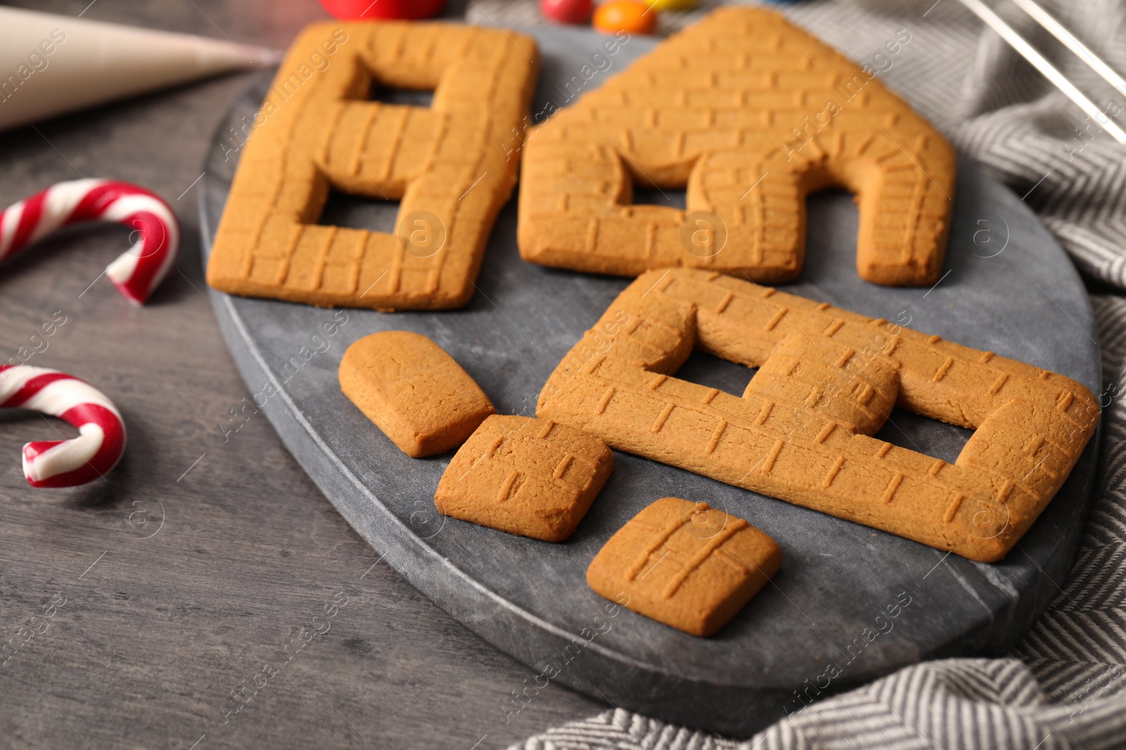 Photo of Parts of gingerbread house on grey table, closeup