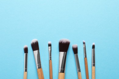 Photo of Different makeup brushes on light blue background, flat lay. Space for text