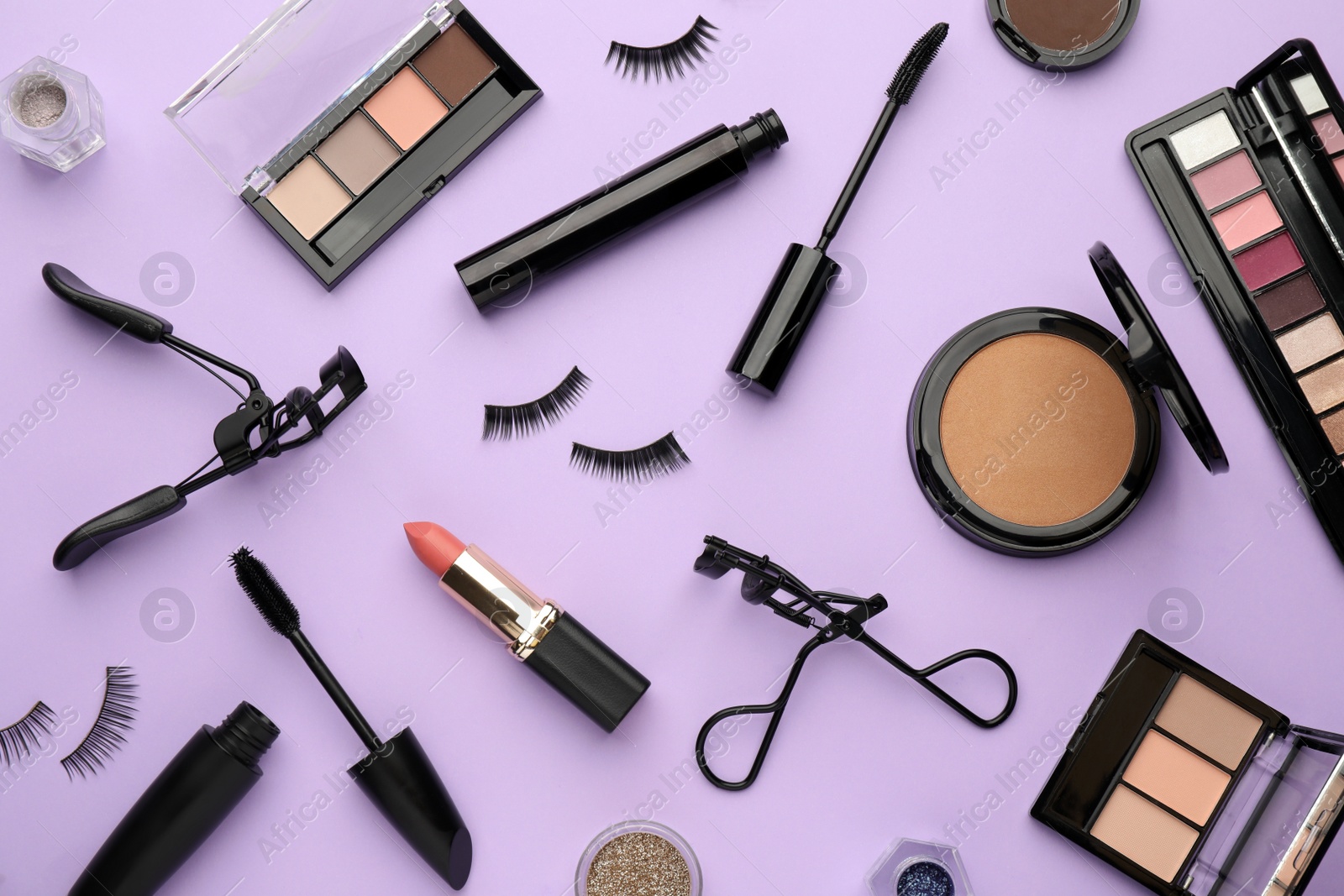 Photo of Eyelash curlers and makeup products on violet background, flat lay