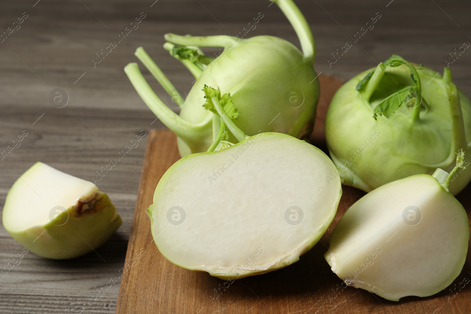 Photo of Whole and cut kohlrabi plants on wooden table, closeup