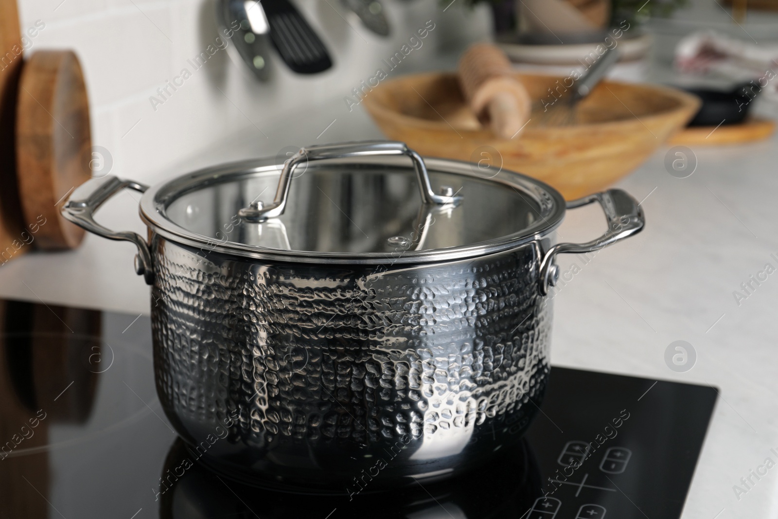 Photo of Metal pot on cooktop in kitchen, closeup. Cooking utensils