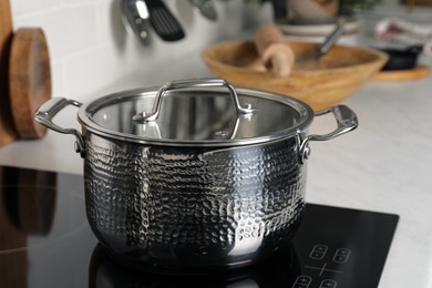 Photo of Metal pot on cooktop in kitchen, closeup. Cooking utensils