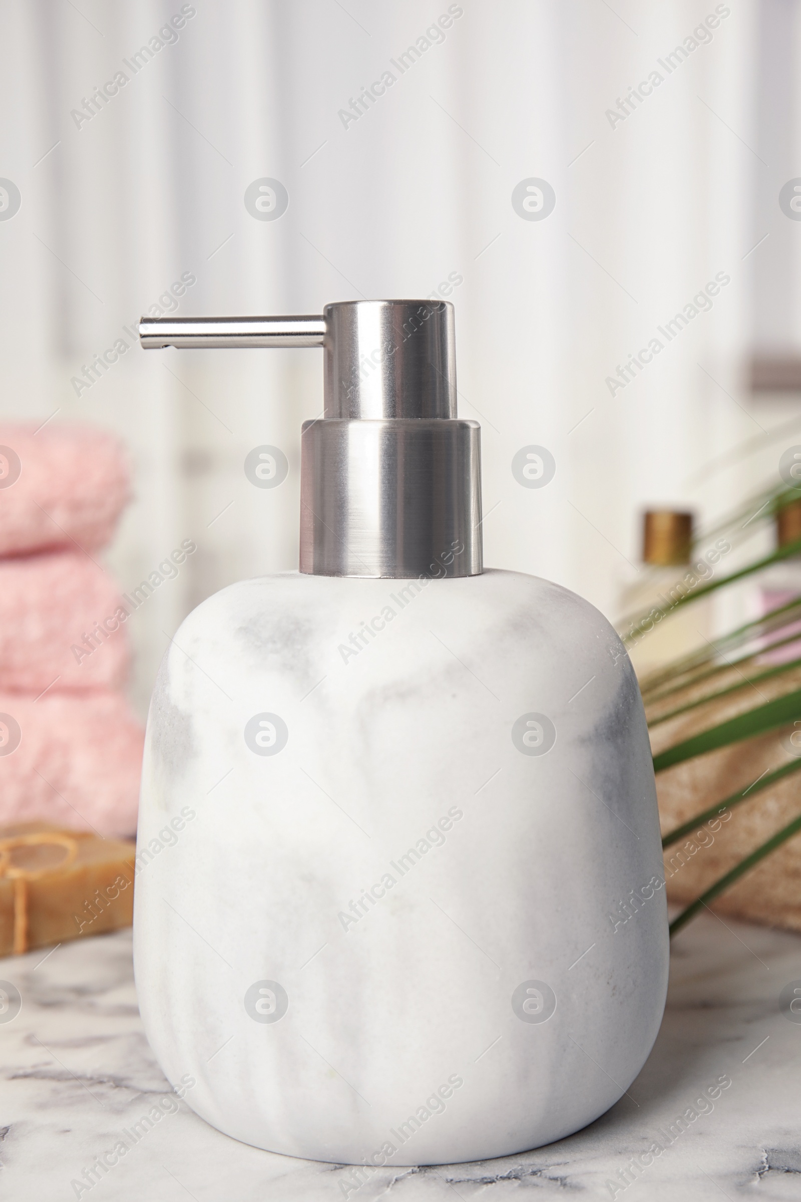 Photo of Modern marble soap dispenser on light table