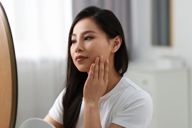 Photo of Woman with perfect skin looking at mirror indoors