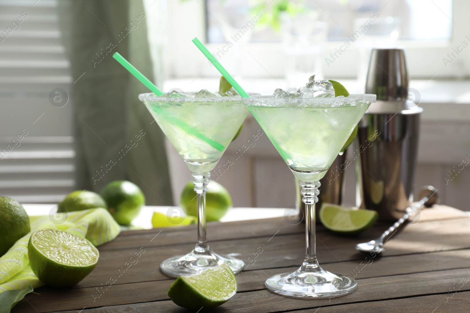 Photo of Delicious Margarita cocktail in glasses and lime on wooden table, closeup