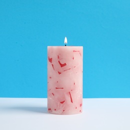 Alight scented wax candle on color background