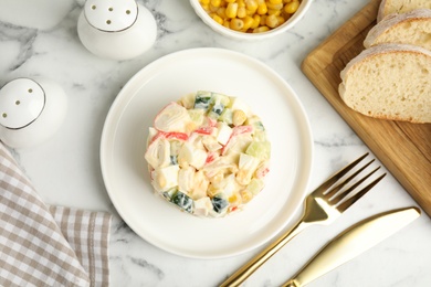 Delicious salad with fresh crab sticks served on marble table, flat lay