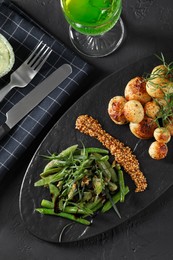 Delicious salad with tarragon, mustard and grilled potatoes served on black textured table, flat lay