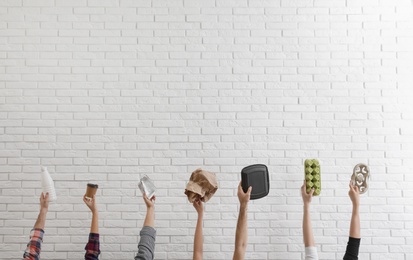 Photo of People holding different garbage against brick wall. Waste recycling concept