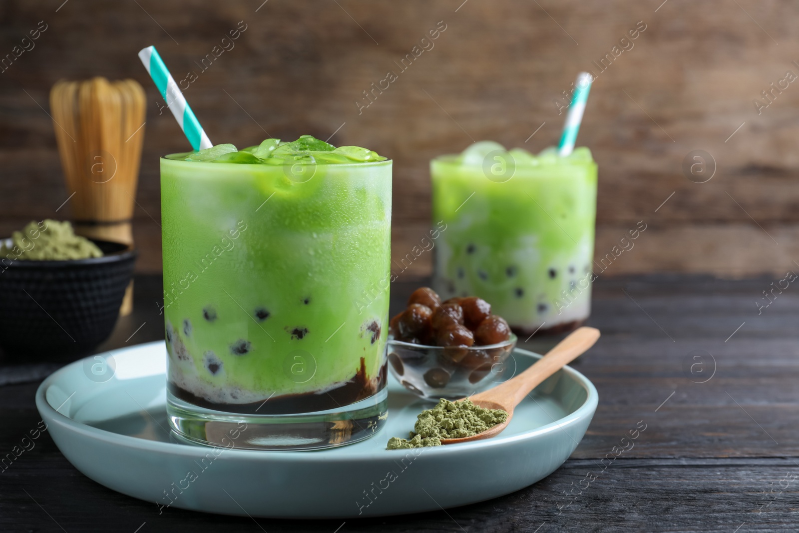 Photo of Tasty milk bubble tea with green matcha on black wooden table, closeup