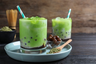 Tasty milk bubble tea with green matcha on black wooden table, closeup