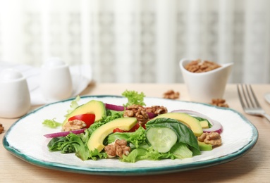 Photo of Delicious avocado salad with walnuts on wooden table