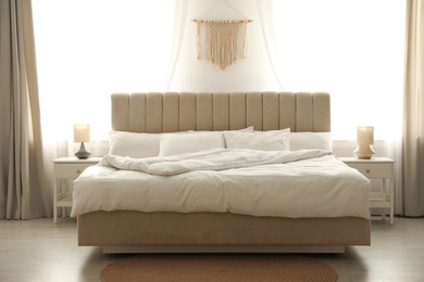 Photo of Comfortable bed with soft blanket in stylish room interior