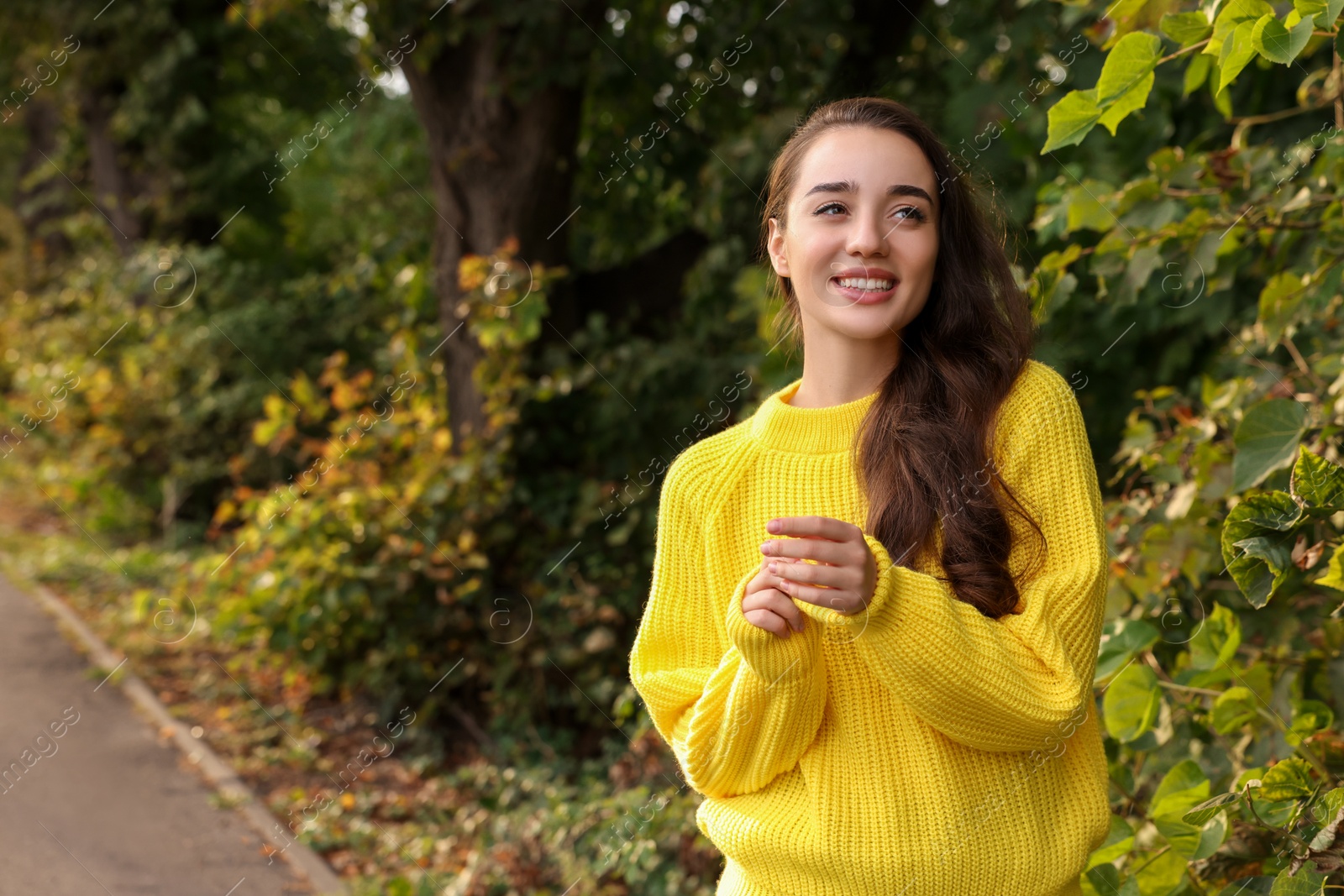 Photo of Beautiful young woman in stylish warm sweater outdoors, space for text