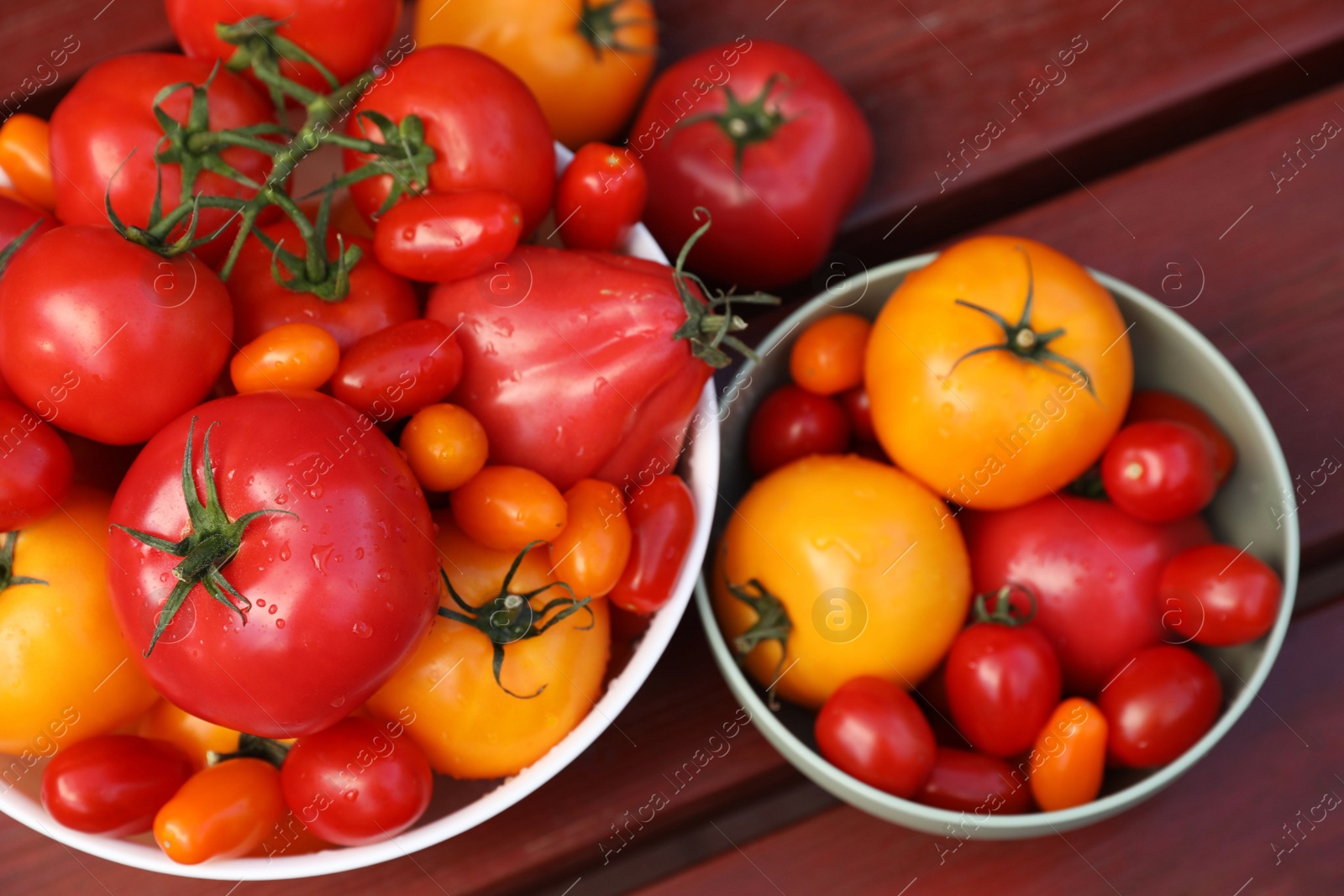 Photo of Bowls with fresh tomatoes on wooden table, flat lay